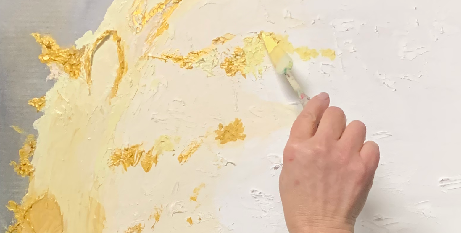 Una mano dipinge con colori caldi su una tela