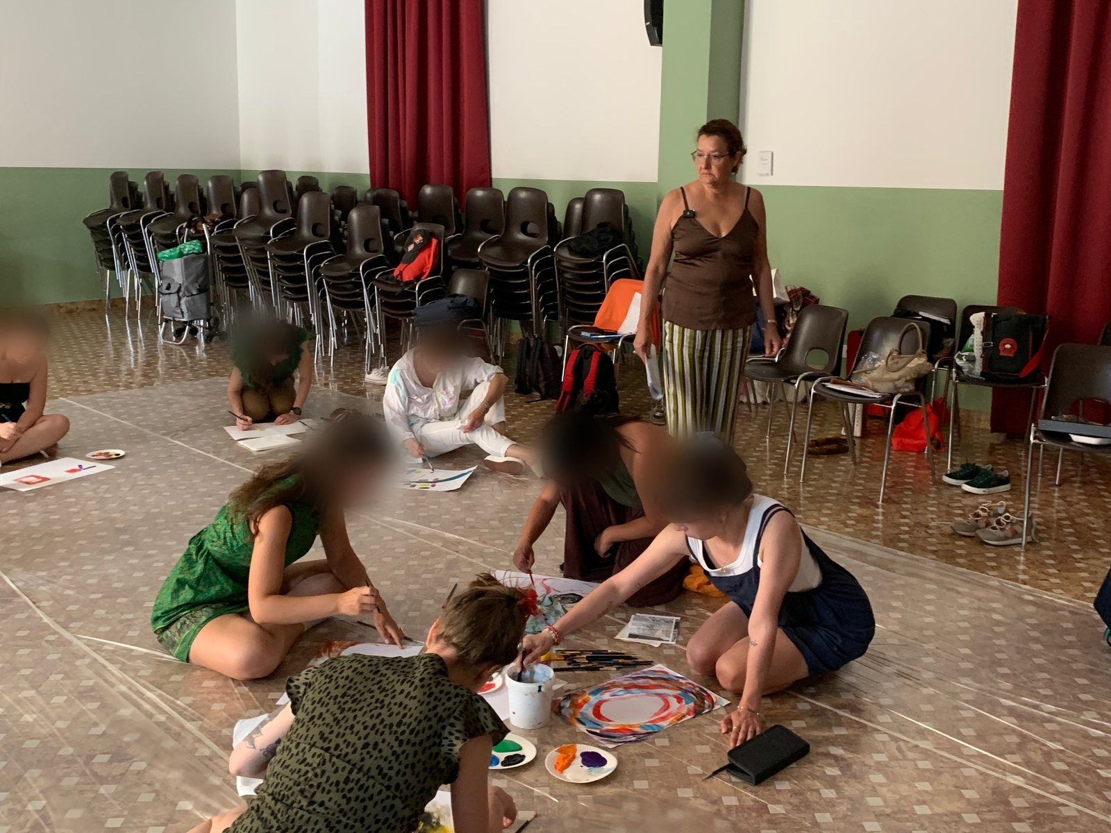 Cristina Zucchi segue un gruppo che dipinge seduto a terra durante un laboratorio di arteterapia